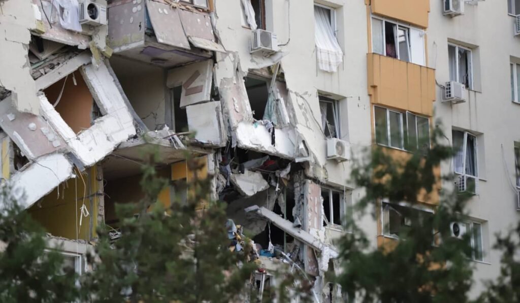 Pereții căzuți ai celor două etaje unde a avut loc explozia din Rahova, bucățile de beton din fațada blocului atârnă în jos. Geamurile de la ferestre sunt sparte și perdelele atârnă de marginea blocului