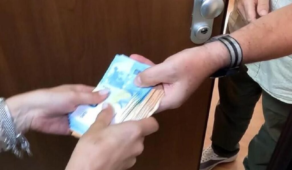 Imaginea arată în prim plan un bărbat și o femeie care țin în mâini același teanc de bancnote