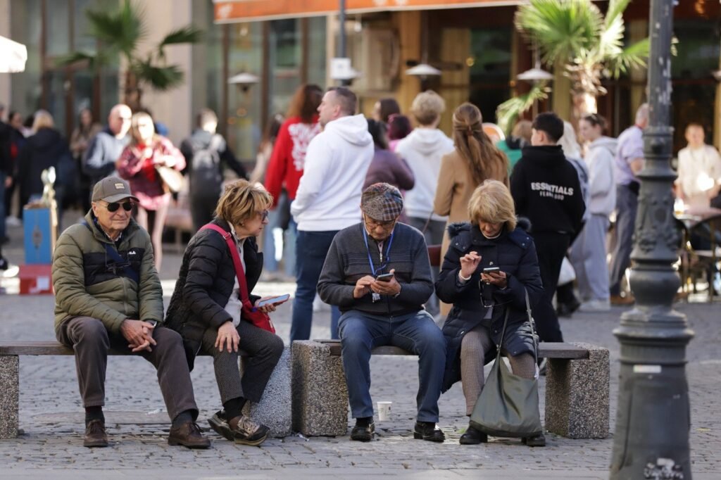 Grup de oameni stau pe o banca. Foto ilustrativ